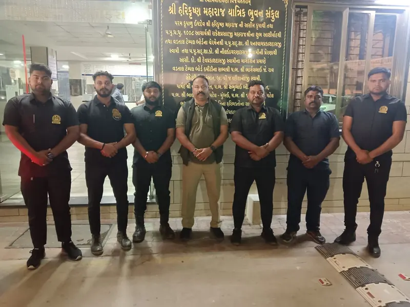 Seven members of the Golden Hawk Security team standing together in front of a building entrance at night