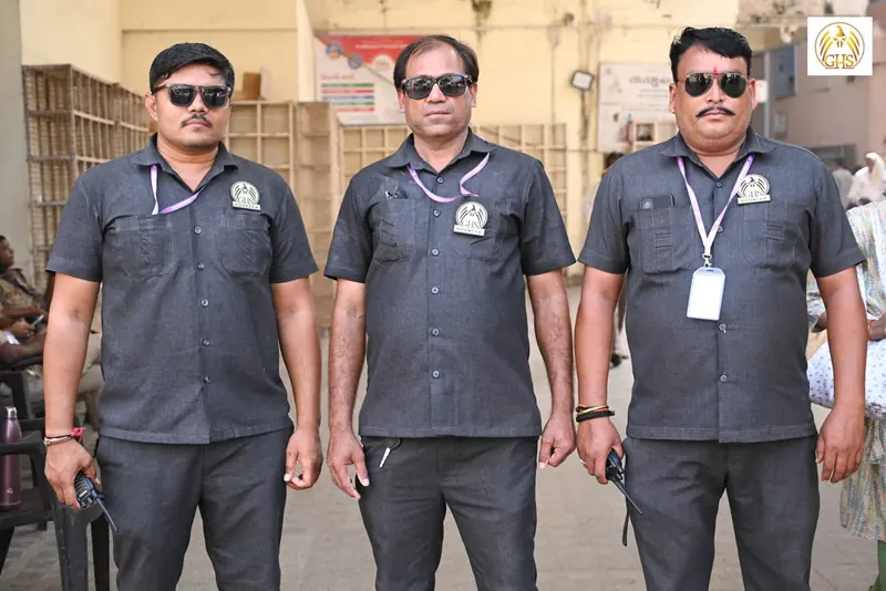 Three guards in dark grey shirts wearing sunglasses and ID cards